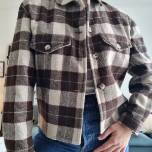 Rutig kort jacka vintage - I storlek M men passar mig som brukar ha storlek S i överdelar. Rutig jacka i ull i olika bruna nyanser, superfin men jag använder tyvärr aldrig den. Den är lite fodrad. Köpt på en vintagebutik där damen valde ut plagg att sälja vidare (sötaste🥲)