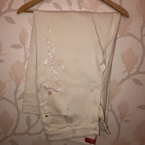 Vita byxor med brodyr - Vita ”ribbade” byxor med broderade blommor. Storlek S/M.