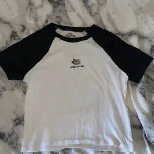 Hollister t-shirt - Vit t-shirt med svarta axlar och ett litet tryck där fram. Har använt den hyfsat mycket med inga tecken på det. Nypris 229kr! buda på den, köp direkt för 159kr+frakt.