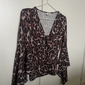 Leopardblus - Leopardblus med utsvängda armar och v ringning. 