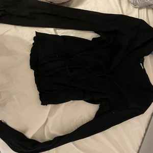 Kofta från HM - Svart kofta från H&M i strl S.  Aldrig använd.  Knyts fram med snöre, ”vågigt” i kanterna 