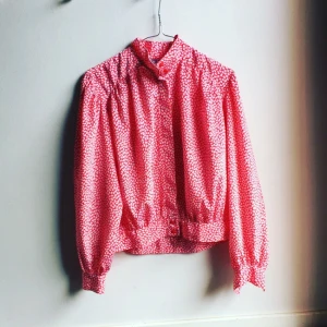 - Fin blus, vintage från London, söt/cool, röd med vitt mönster, blusad i ärm och kropp. Kort modell går till midjan. Polyester 