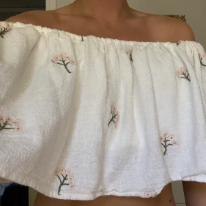 Vit offshoulder topp med blommor från Zara  - Säljer en vit offshoulder topp med blommor från Zara. Nästan helt oanvänd i storlek L men passar mig som brukar ha storlek S. 