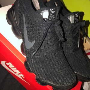 Nike vapormax flyknit strl 40, passar 39 - Ett par Nike Vapormax flyknit skor köpta ifrån Asos år 2018 för 2100kr. De är små i storleken därför passar de även 39, vilket är min strl. Skorna har ett hål i plasten men som man kan fixa enkelt. Annars är de som helt nya! Pris kan diskuteras.