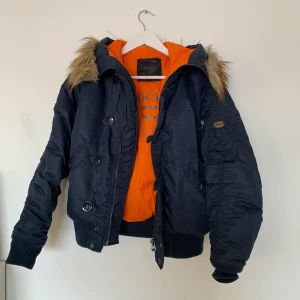 Crocker Vinterjacka storlek S - Varm vinterjacka. Orange på insidan, mörkblå på utsidan. Armficka samt vanliga fickor finns. 