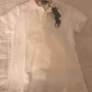  - Oanvänd vit pikétröja från Ralph Lauren.  Lapparna kvar. Storlek S, passar även XS. 