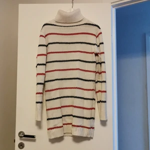 Stickad figursydd "pippitröja" - Lång figursydd stickad tröja. Med hög hals. Röd och blå randig. 