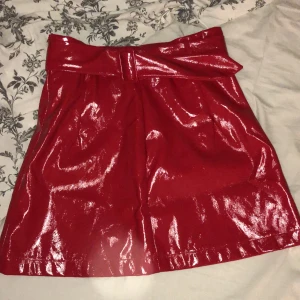 Röd kjol vinyl  - Helt ny oanvänd kjol i glansigt vinyl-material, passar 36-38