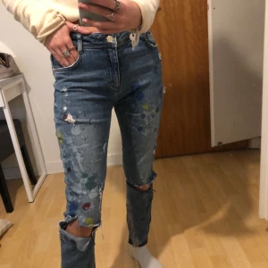 Jeans från Zara med målarfärg på  - Jeans från Zara med skvätt målarfärg lite överallt. Det är hål på knäna och bak under rumpan är det ett vitt tryck. Storlek 36 men små i storleken. Säljer för 100kr+frakt.