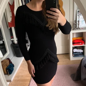 Klänning - Svart lyxig klänning med tassels från Missguided. Oanvänd. Sitter som ett smäck och har ett material som smiter åt smickrande. Väldigt stretchig och bekväm.