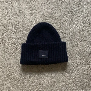 Acne mössa, mörkblå med vit gubbe - Stickad mörkblå acne mössa. Kostade 1 095 kr.