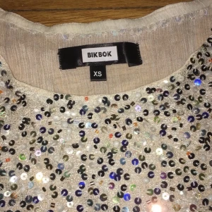 LINNE FRÅN BIK BOK / storlek XS  - Säljer ett glittrigt linne från Bik Bok storlek XS. Säljer pga av att det är för litet för mig. 50 riksdaler tack! 
