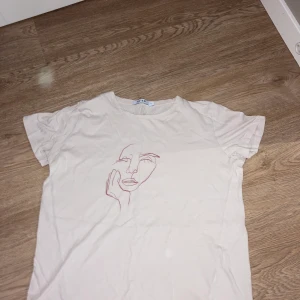 T-Shirt  - Beige T-shirt med tryck. Har använt enstaka gånger och har ett mjukt och elastiskt material.