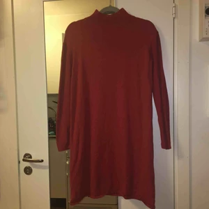  - Koppar/orange färgad klänning med ribbade ärmar, hög hals och knappar längs axeln på vänster sida. 145-150 cm lång. 95% bomull och 5% kashmir. Kan mötas upp alt. skicka.