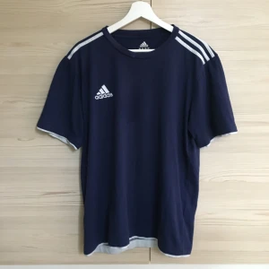 Adidas t-shirt - Mörkblå adidas t-shirt som är jätteskön och bra. Den har en liten ljus fläck på kragen men annars i fint skick. Frakt ingår i priset! O pris kan diskuteras❤️