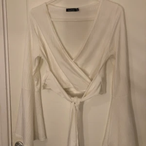 Blus med knytning  - En vit ribbad blus från Boohoo, använd fåtal ggr, stretchig med vida armar 