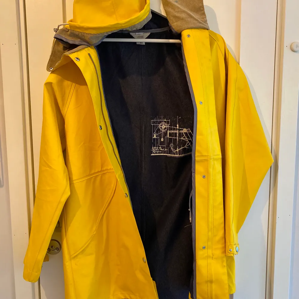 En sparsamt använd regnkappa i lite längre modell. Detaljer av manchester likande typ i kragen, snörning i huvan för att justera storleken. Den har både blixtlås och knappar. Köparen står för frakten.. Takit.