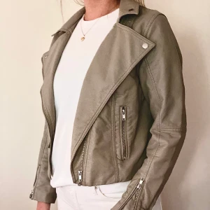 Skinnjacka - Beige/grå jacka i skinn imitation i stl. 38 från H&M. Knappt använd, så i bra skick. Snygg modell som är lagom lång.