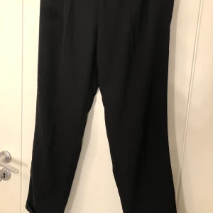 Svarta kostymbyxor - Svart kostymbyxor med uppvikna anklar, knappt använda, resor i midjan 