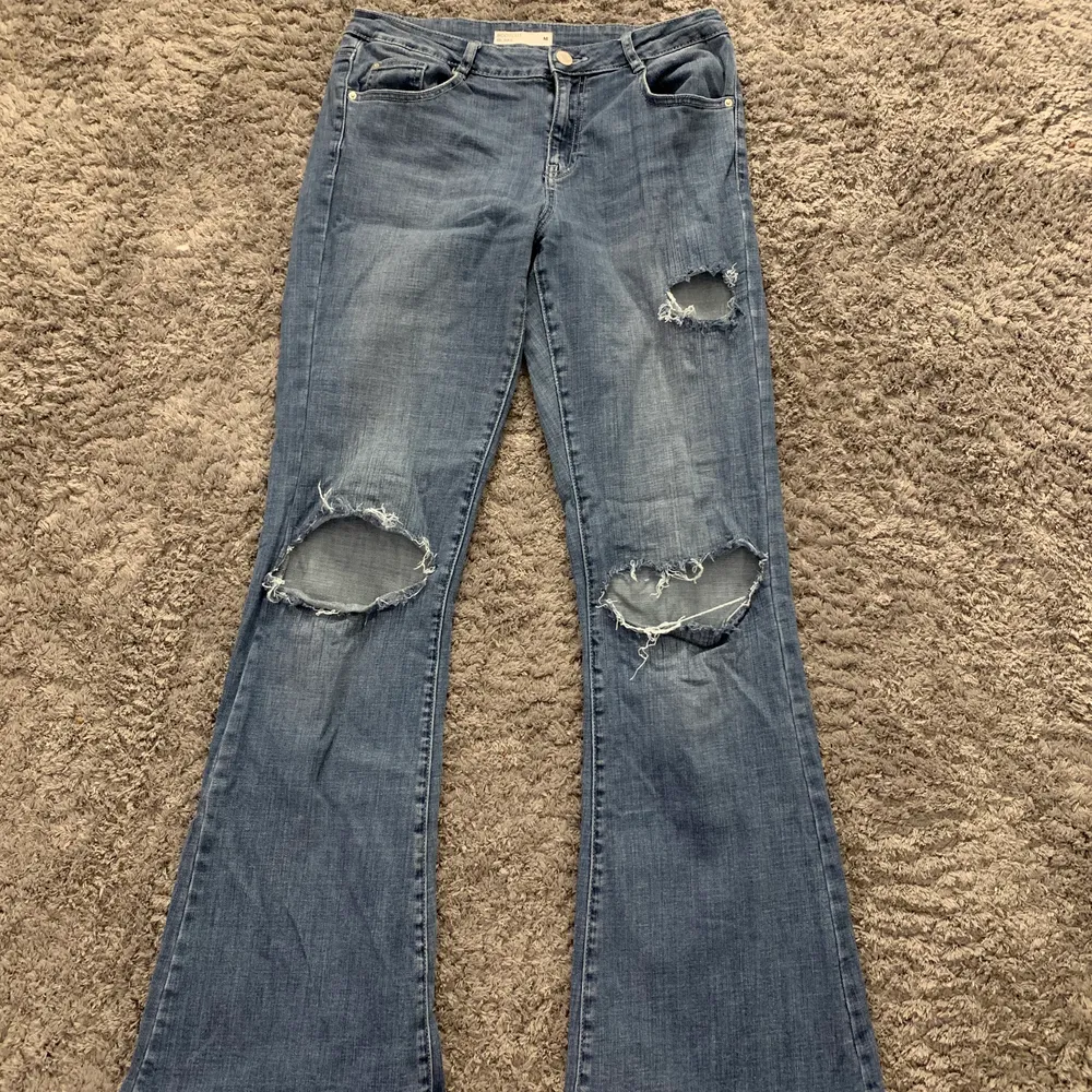 Blåa bootcut jeans från Bik Bok med hål i knäna som jag gjort själv. Mycket fint skick, nästintill oanvända. Frakt 66 kr. . Jeans & Byxor.