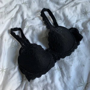 Svart BH  - Jättefin svart bh i nyskick, köpte fel storlek! Verkligen jättesöt med en liten svart ros mellan brösten. Bjuder på frakt!