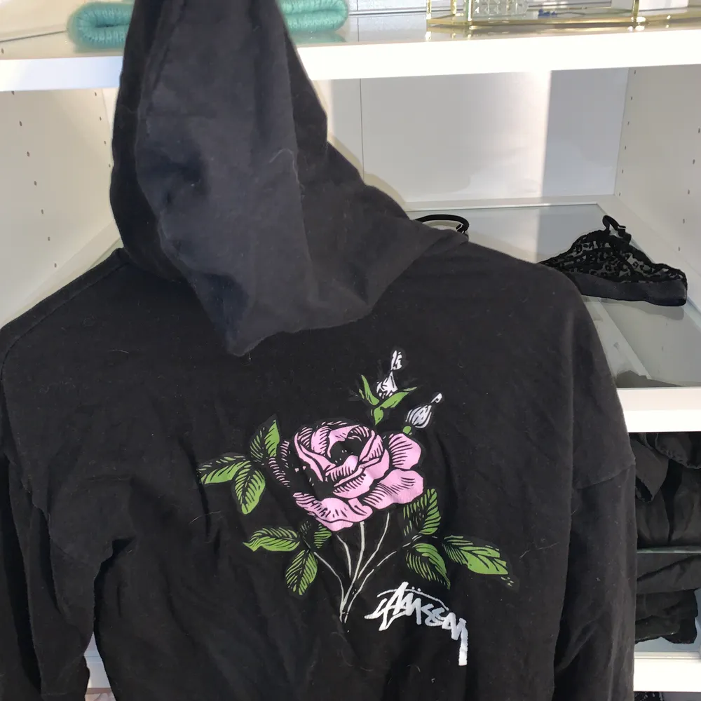 Stussy hoodie med tryck på ryggen, svart med lila/rosa blomma. Kan inte hitta den någonstans på nätet så troligtvis helt slutsåld💕 xs-s. Hoodies.