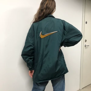 Nike jacka - Snygg vintagejacka från Nike, fodrad o med fet logo på ryggen! Finns några fläckar på skuldran. Personen är 170cm! 🥰