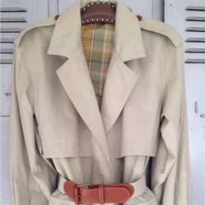  - beige med cognacsfärgade knappar och läderspänne på bältet. rutigt foder upptill och i ärmar. längre variant och ganska tunn och lätt, perfekt till vår & sommar. det finns fler detaljfoton.