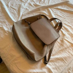  - En ryggsäck från Åhléns. Den är beige och aldrig använd  