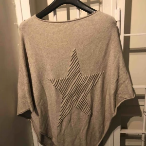  - Härlig beige poncho med stjärna fram. Finstickad. Varm & skön. Material: 50% viscose 28% polyester 22% nylon 