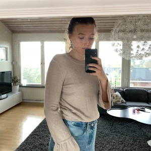 Guldigt festtröja. - Superfin guldglittrig tröja. Kan användas till vardag också men går att styla upp till fest. Jättefina volanger på sidan. Använd ca 5 ggr