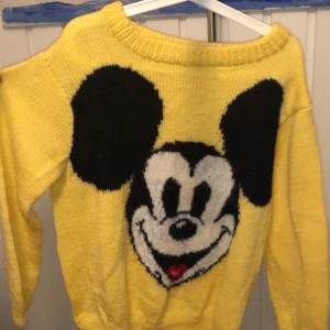 Gul stickad tröja med musse pigg  - Gul stickad tröja med musse pigg på. Själv gjord. Lite båtringning. Sydd på 80-talet ungefär, sparsamt använd. 50kr frakt