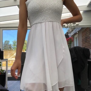 Vit finklänning - Vit finklänning i storlek xs med stretchig midja och tajt byst. Bysten har blivit sytts om till en cm kortare än originalet. Kort där fram och längre bak. Klänningen är endast använd ett fåtal gånger. OBS har två axelband 