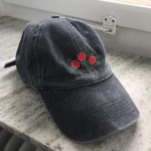  - Grå keps med broderade rosor, helt ny med lappen kvar! Ställbar bak så passar alla. Nypris 154 kr. Kan mötas upp i Stockholm eller skicka mot fraktkostnad