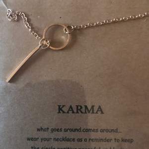 Guld pläterat halsband med symbol för karma. Text med råd medföljer