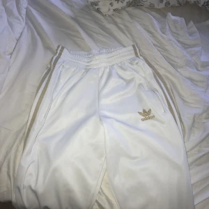  - Vita adidas byxor med guld, fint skick säljer billigt för de fläckar längst ner på byxorna men de är inget man tänker på. Står det är en M men dom är mer som XS/S! Fraktar och tar emot swish!😊