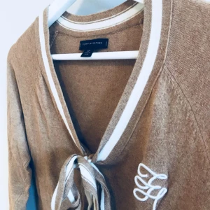  - Tommy Hilfiger  Storlek S 52% cotton 20% viscose 19% nylon 5% angora Beige brun V-ringad tröja med fina detaljer Fint skick, använd ett fåtal ggr Nypris 1000 kr