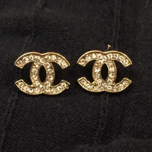  - Chanel örhängen med strass. Guldfärgade. Aldrig använd. Mått cirka 2-2,5cm.