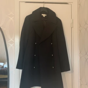 Svart kappa från H&M i storlek 38 - Medellång svart kappa i storlek 38