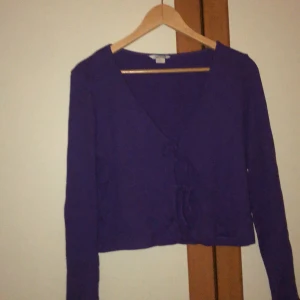 Lila kofta från monki - En lila kofta från monki. Det är två par av band man knyter där fram. Använd två gånger.