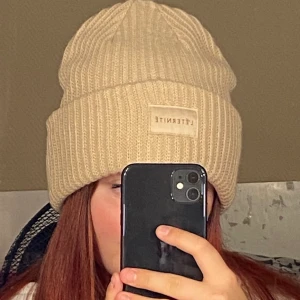 Mössa - En skit snygg latte färgad mössa med ett tryck i mitten🧡 passar as bra nu till höst och vinter, oanvänd✨🤍💛✨ köparen betalar frakten😙