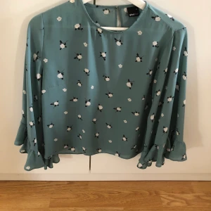 Söt blus med blommor - En söt blus med blommor från Gina Tricot. Storlek 36 men passar 34 och 38 tror jag. Färgen är grön med vita blommor. Köparen står för frakten.