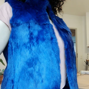  - Snygg pälsväst i blått. Super len! Köpte på marknad i London några år sen. Ståkrage, stängning fram med hylsor. Snygg att ha över en jacka eller tröja. 