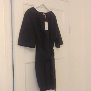  - Fin svart klänning med knytband i midjan, aldrig använd då jag tyvärr fick fel storlek i present. 