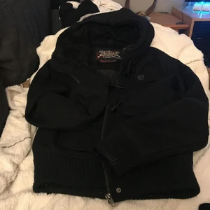  - Kort fodrad duffel i svart. Dragkedja och hajtandsknappar. Luvan ej avtagbar. 