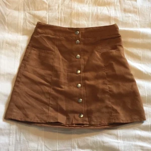  - Kjol i mocca-liknande material från H&M! Två små diskreta fickor framtill. Fint skick! Fraktas eller möts upp i linköping