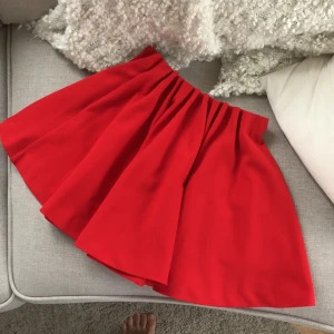  - Fin klarröd kjol med vackert klockat fall. Resår i midjan. Rejäl struktur. Passar 34-38. Aldrig använd!  Köparen betalar frakten på 45 kr. 