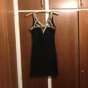 Svart klänning med metallicdetaljer från nelly.com. Använd ett fåtal gånger. Storlek XS