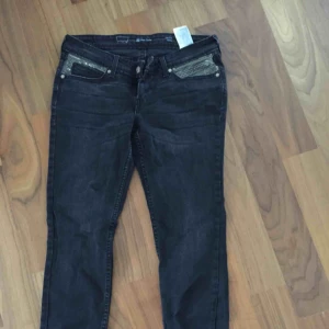  - Svarta Levis demi curve jeans. Dragkedjor vid bensluten och snygga pärldetaljer vid fickorna. Midja 30 längd 32. Aldrig använda på grund av fel storlek. Frakt på 50kr tillkommer.