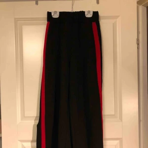  - Balongbyxor med en röd söm på sidorna. Har även en slits vid byxbenets slut